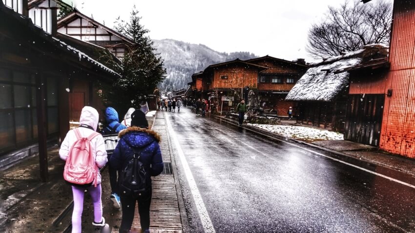 Falling Snow and People in Jackets Walking on an Empty Streets 