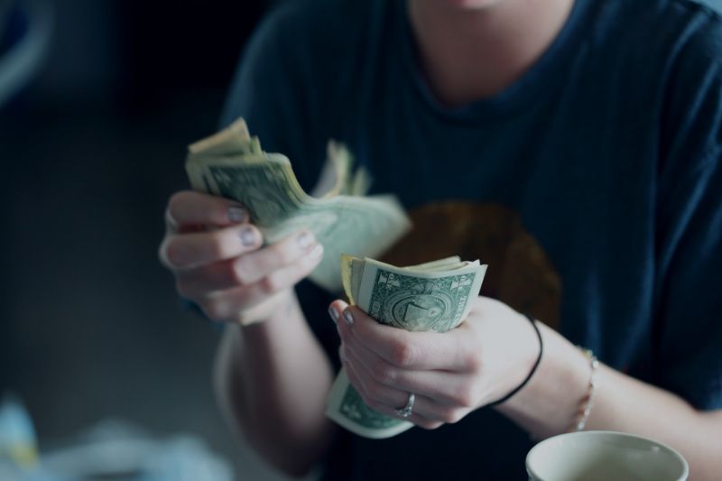 Woman Holding and Counting Paper Bills