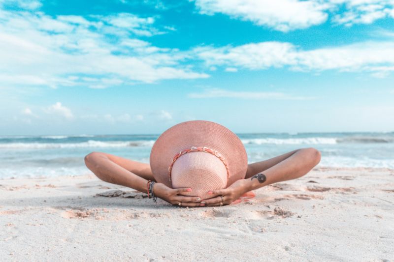 Woman wearing a hat laying on a sand