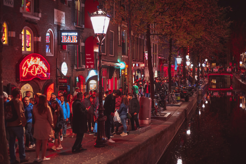 Crowd of international tourists walking on streets of Red Light District of Amsterdam