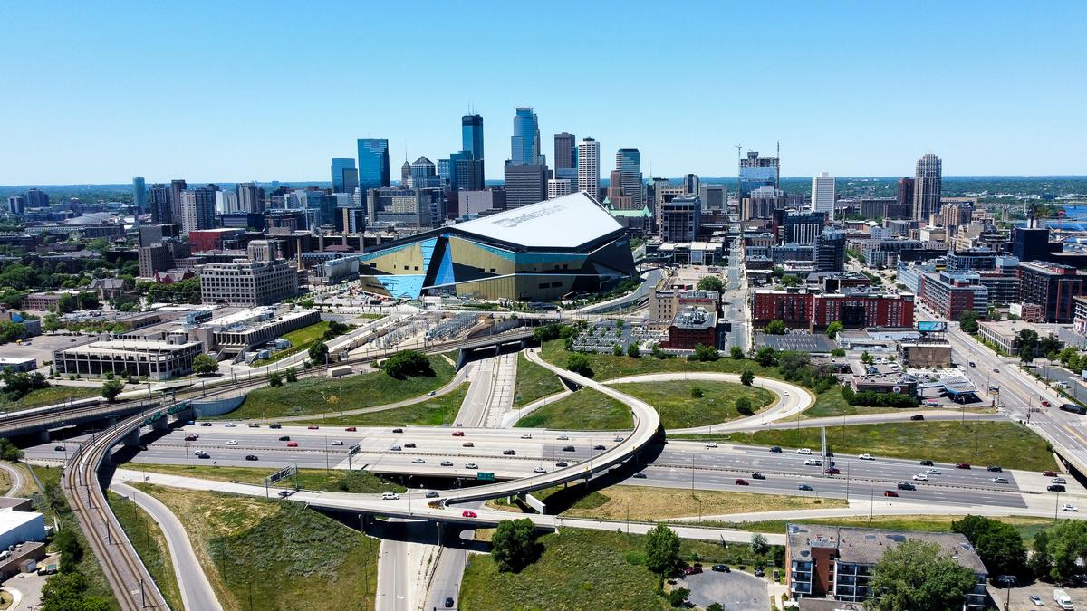 Aerial view of East Minneapolis skyline with stadium, traffic, and urban landscape on a sunny day.