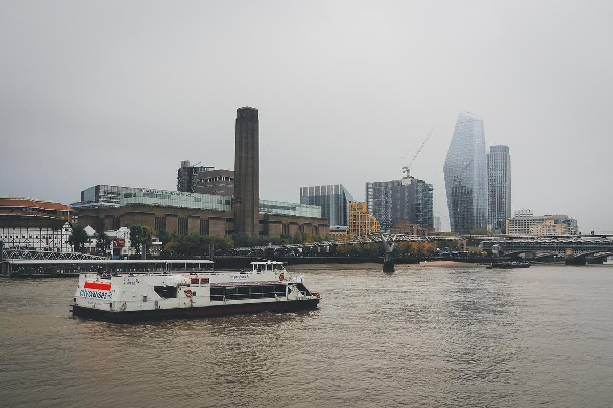 Iconic view of Tate Modern and River Thames with City Cruises boat, contemporary architecture, and overcast London sky