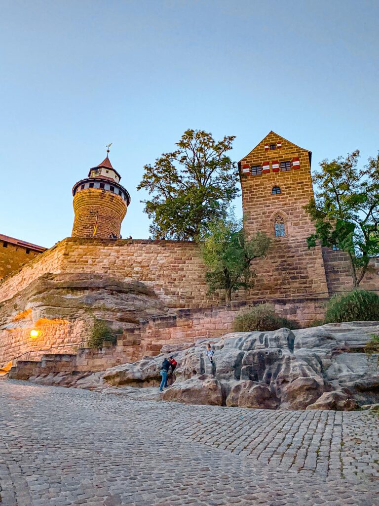 Imperial Castle of Nuremberg at dusk with visitors, showcasing medieval architecture and historical significance in sRGB color space.