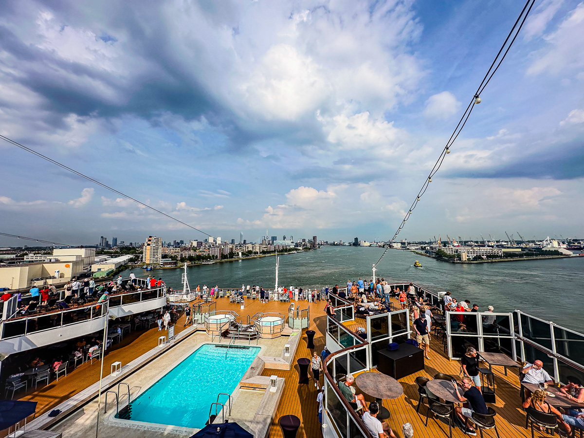 MS Rotterdam adult pool deck with Rotterdam skyline and harbor, relaxing Holland America cruise