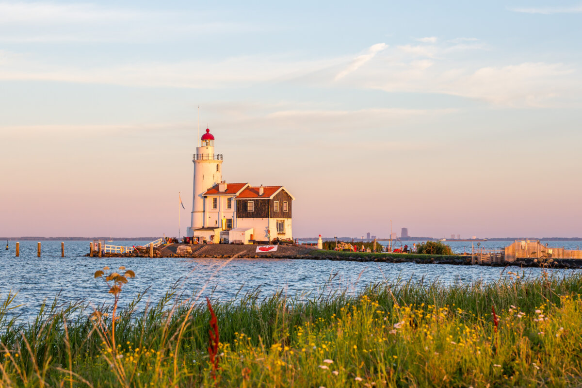 Paard van Marken lighthouse on marken island in golden hour with blue sky and sea with grass in foreground