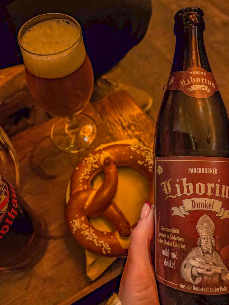 Paderborner Liborius Dunkel beer and soft pretzel in cozy European setting, inviting indulgence in authentic German flavors