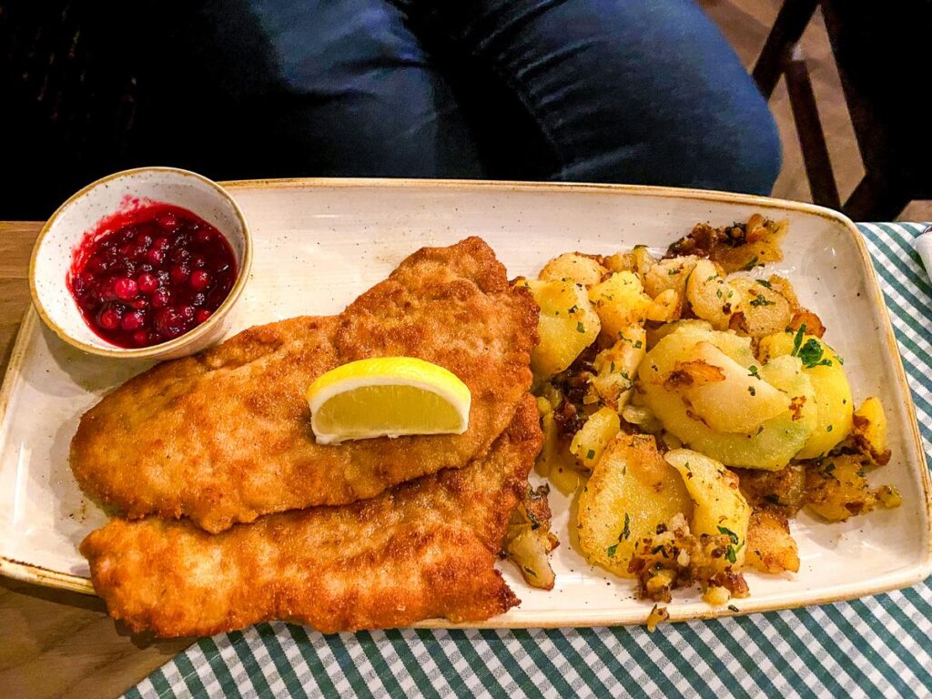 Traditional German Schnitzel with seasoned potato salad, lemon, and cranberry sauce served at Augustiner in Munich, Germany.