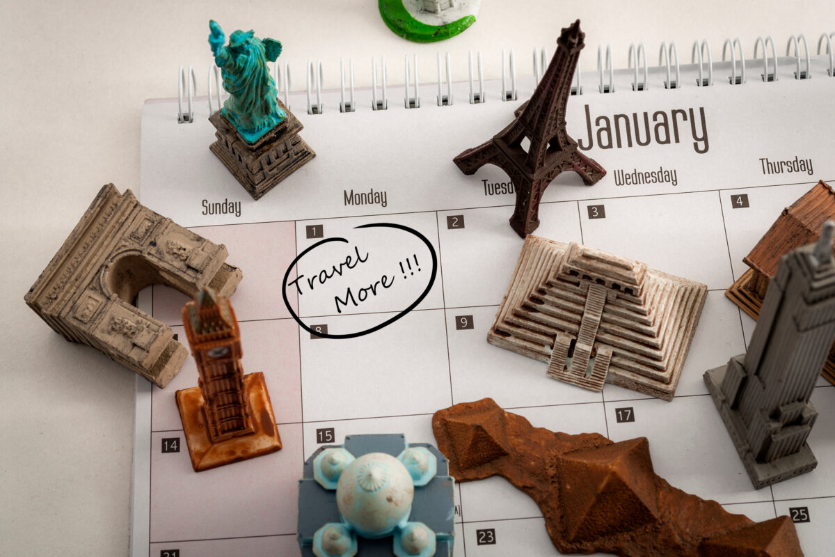 New year resolution and the desire to travel more concept with a calendar with january first circled and famous world landmarks