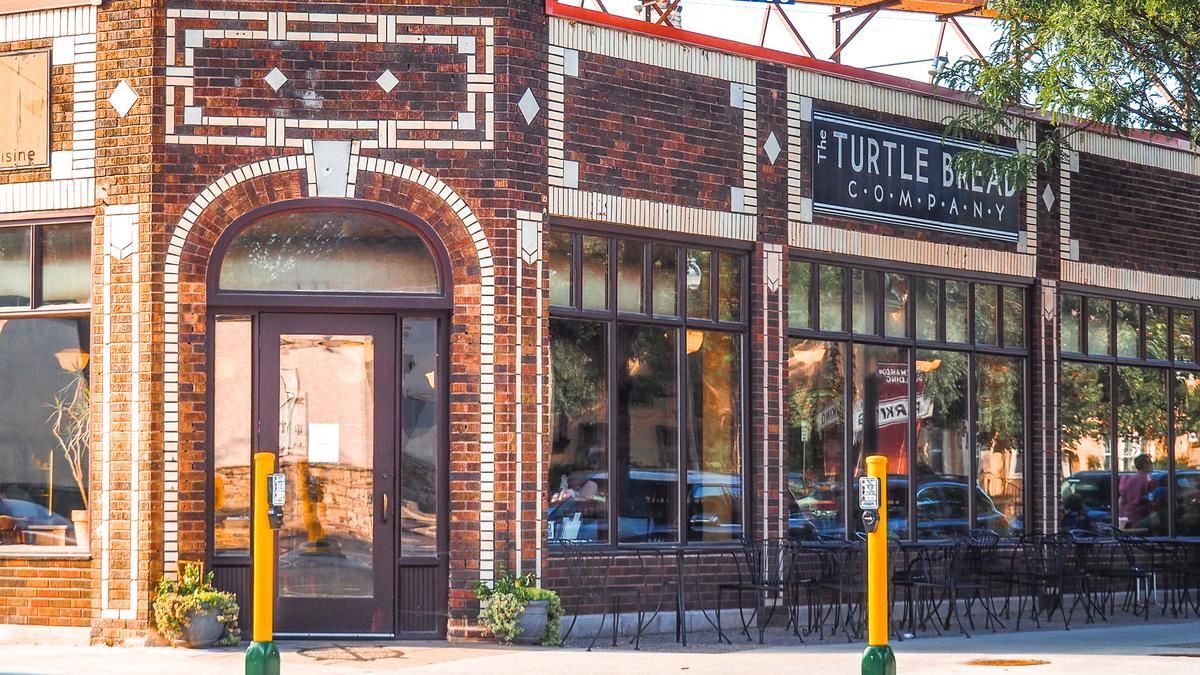 The Turtle Bread Company storefront in Minneapolis with clear windows and outdoor seating under bright sunlight.